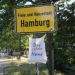 Ein Weisses T-Shirt mit der Aufschrift das letzte Hemd unter dem Ortseingangsschld Hambugr